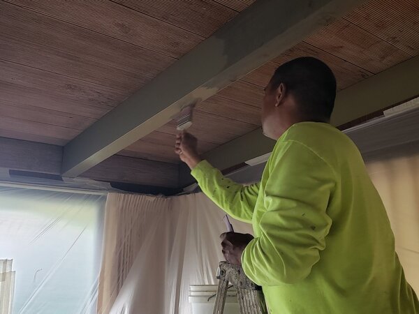Brush painting a beam in a home
