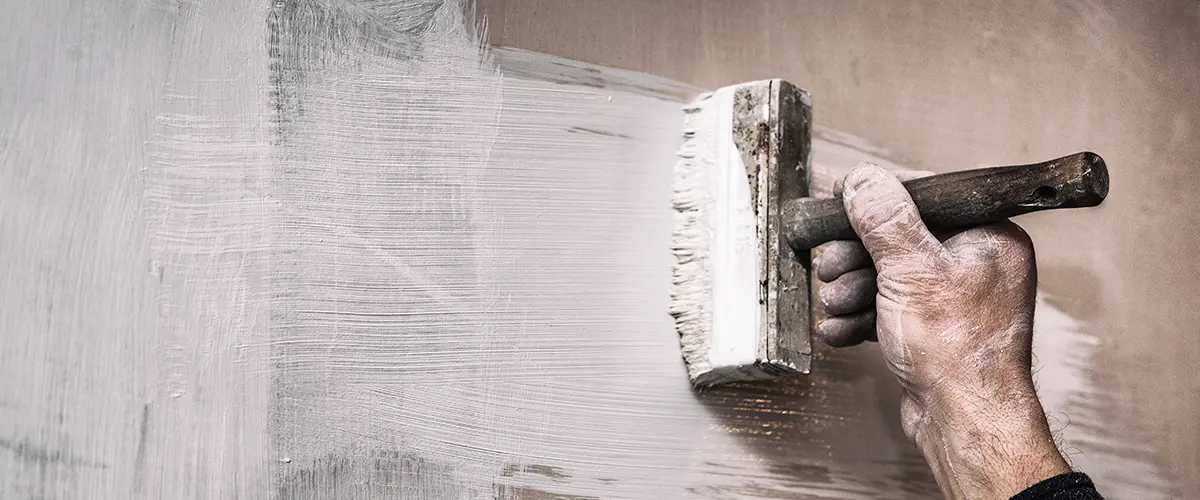 applying primer on a wall before applying a decorative layer of plaster