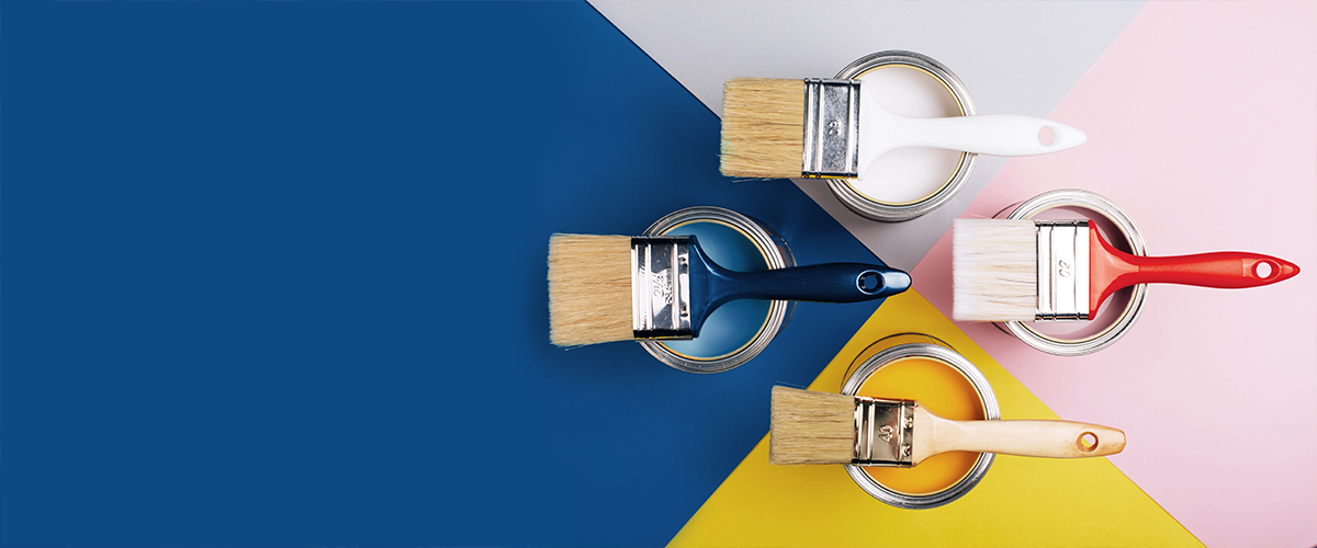 Various paint brushes rest on open paint cans filled with different colors on a multi-colored background.