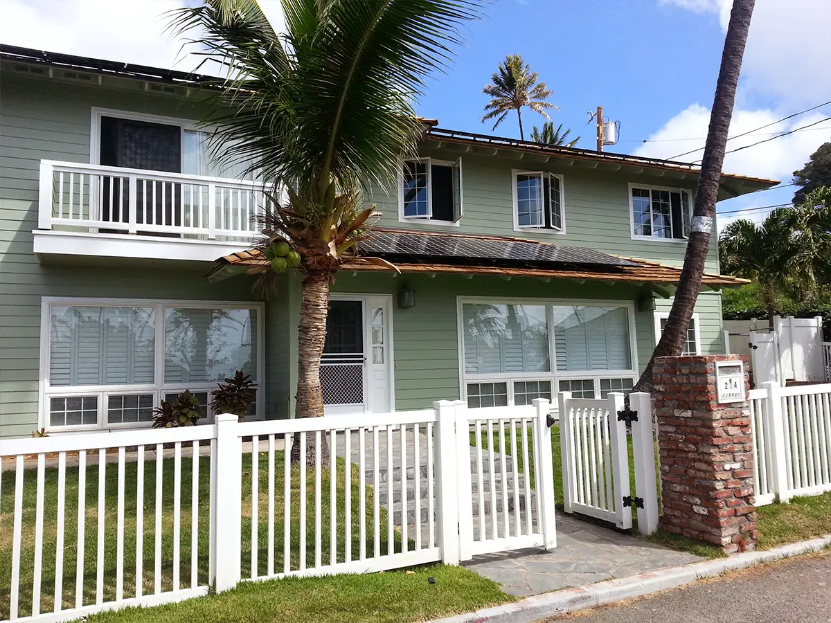 Exterior Painting Companies in Mililani, HI 4 Green two-story home with white fence, palm tree, and large windows in a tropical setting.