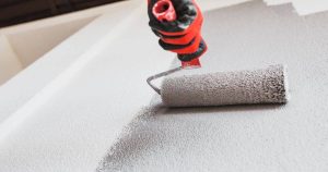 Painting Over Wallpaper: How To Best Do It And More 2 Close-up of paint roller coating a textured exterior surface