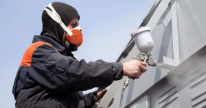 Blog 4 Close-up of spray painting on a metal surface with protective gear