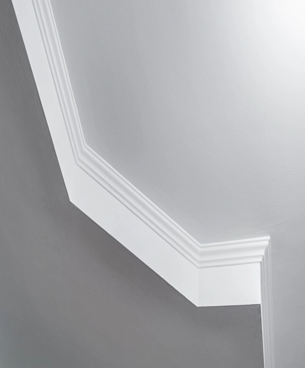 Close-up of sleek white crown molding painted seamlessly against a grey wall corner.