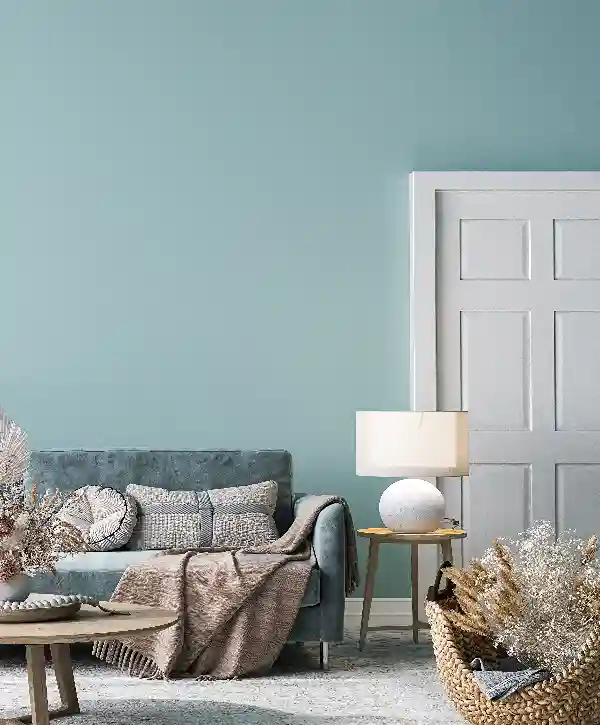Top 8 Interior Painting Companies In Aiea, HI 1 Cozy living room featuring fresh light blue interior painting on the walls, a grey sofa, a white door, and rustic woven basket decor in Aiea, HI.